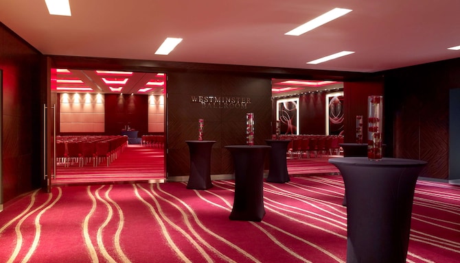 Empty reception space with pink lighting, cocktail tables and Westminster signage