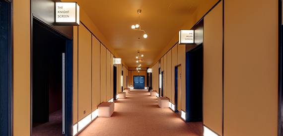 Corridor with numbered screen doors and wall-mounted lighting