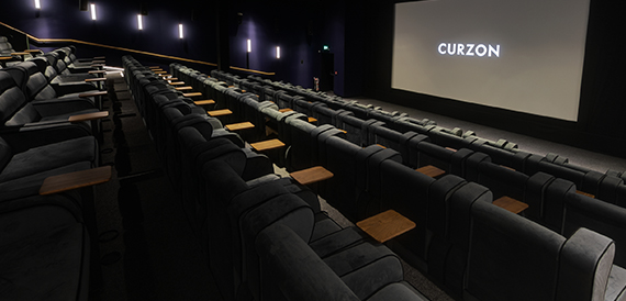 Cinema screening room with fold-down tables between rows of grey seats