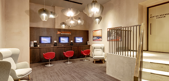 Self-service ticket kiosks with red stools beside a staircase