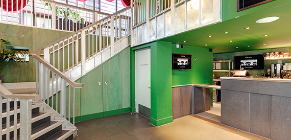 Stairwell corridor with a till counter, green panelling and a wall screen