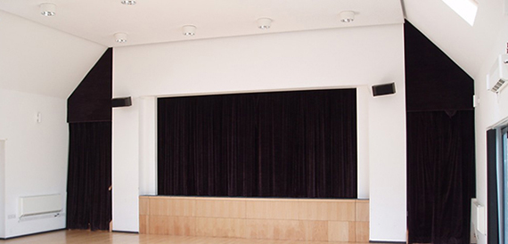 Cinema auditorium with curved rows of red seats facing a screen