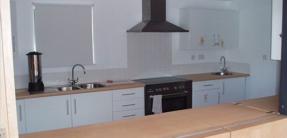 Small fitted kitchen with a hob, sink and wall-mounted cupboards
