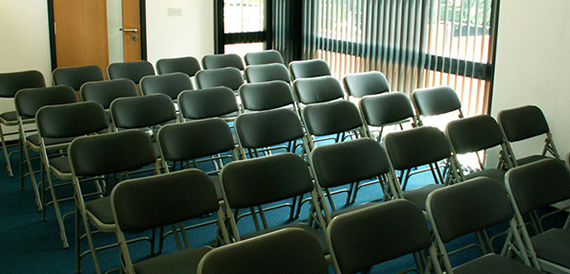Curved cinema auditorium with red seats and small side tables