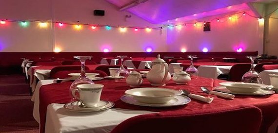 Table set for a tea party with fine china and string lights