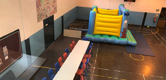 Hall set up with a bouncy castle and tables for a children's party