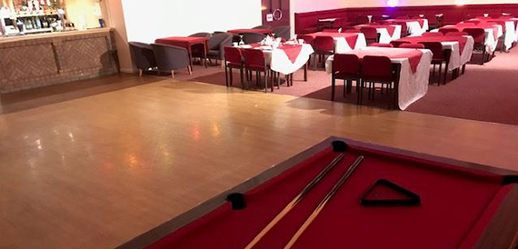 Pool table in the foreground with dining tables set beyond