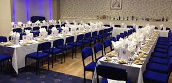 Long tables set formally with blue chairs for a group meal