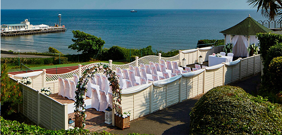 Outdoor wedding ceremony seating with a floral arch overlooking the pier