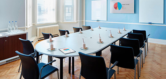 Boardroom with an oval table, blue walls and whiteboard displays