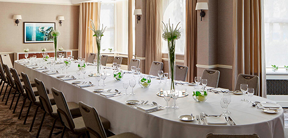 Long private dining table dressed formally with tall floral centrepieces