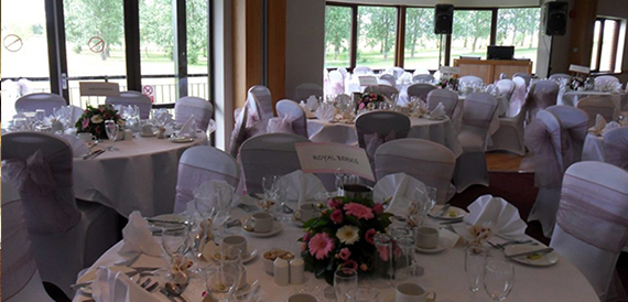 Round tables with pink floral centrepieces and grey chair covers