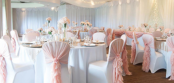 Round tables with blush pink ruffled chair sashes and floral displays