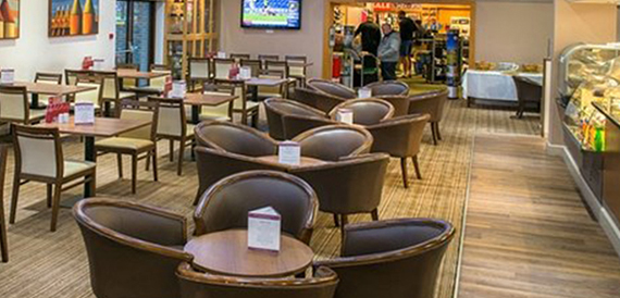 Clubhouse lounge with wicker armchairs, TV screens and golfers relaxing