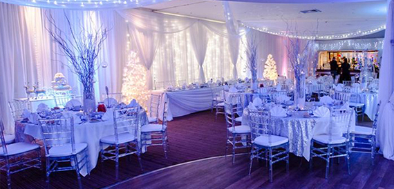 Function room set for a winter event with silver chairs and lit trees