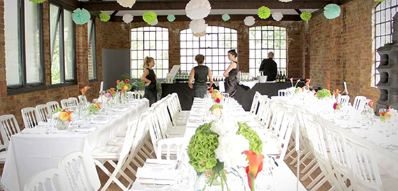 Long tables set for a party with paper pompoms and catering staff