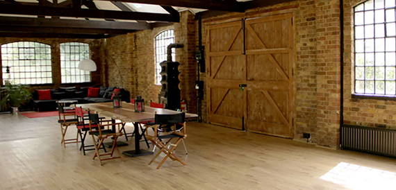 Brick-walled studio with wooden barn doors and a dining table
