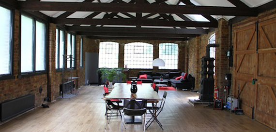 Exposed brick studio with wooden beams, a red sofa and dining table