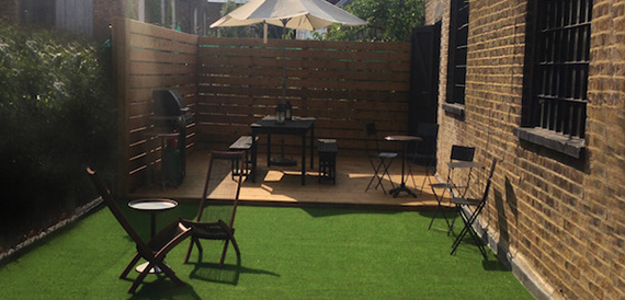 Outdoor courtyard with artificial turf, a parasol and black furniture