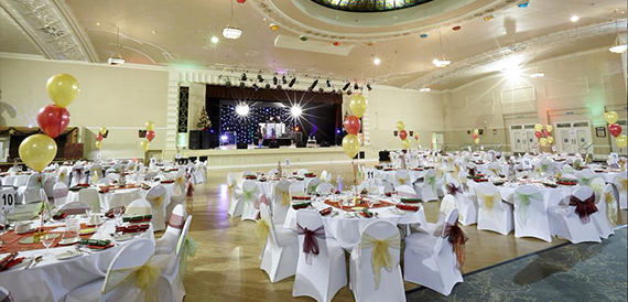 Ballroom with stage lighting and round tables set for a party