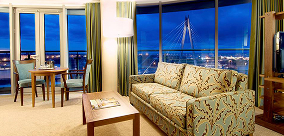 Hotel lounge with a patterned sofa and evening view of a suspension bridge