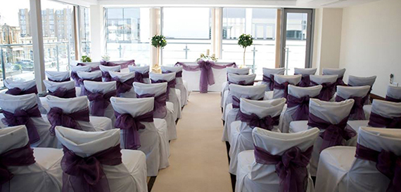 Rows of chairs dressed with purple sashes set for a ceremony