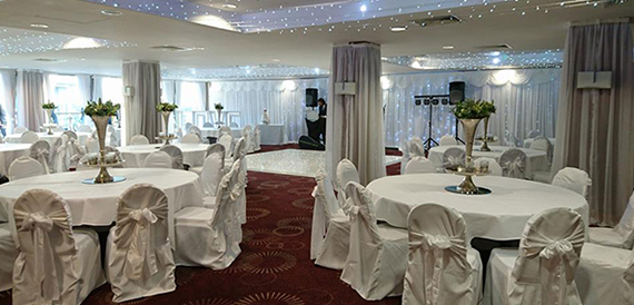 Event room set with white chair covers, fairy lights and a DJ booth