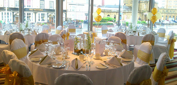 Round tables dressed for a celebration with white covers and gold sashes