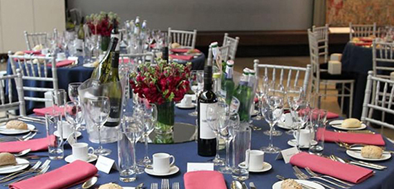 Banqueting table dressed in navy linen with pink napkins and wine