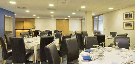 Function room with round tables and dark leather chairs