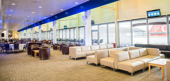 Lounge with cream sofas and dining tables overlooking the pitch
