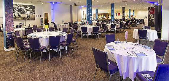 Hall set with round tables and purple chairs beside sponsor branding
