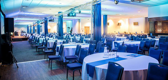 Hospitality suite with round tables in blue linen overlooking the pitch