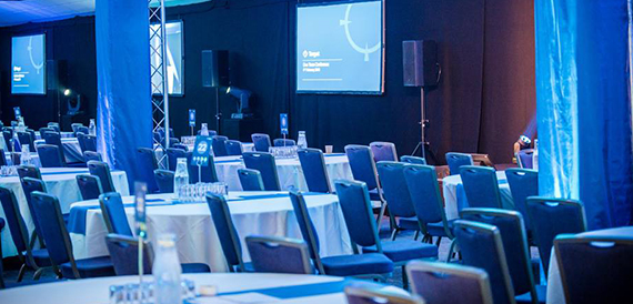Conference room set theatre-style with blue chairs and truss lighting