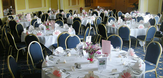 Wedding tables set with navy chair covers, pink flowers and place cards