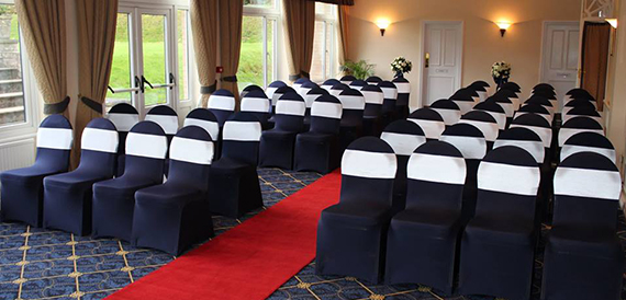 Ceremony room with navy and white chair covers either side of a red aisle carpet