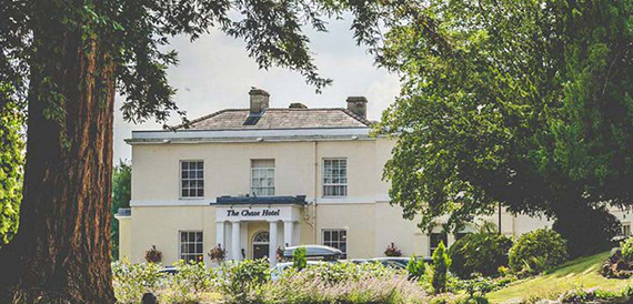 The Chase Hotel's cream exterior with hanging baskets and mature trees
