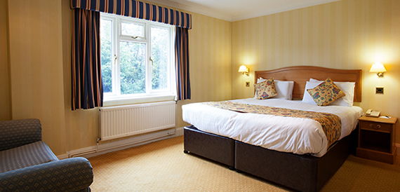 Hotel bedroom with a double bed, striped curtains and a blue armchair