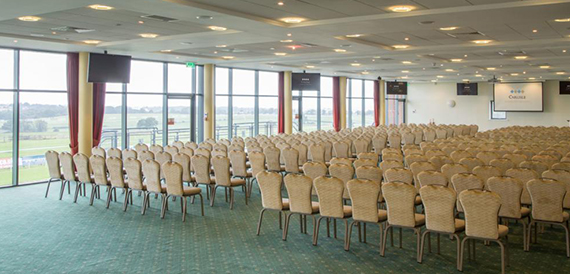 Conference room set theatre-style with wicker chairs and racecourse views