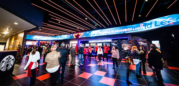 Cinema foyer with a chequered floor, ticket kiosks and visitors queuing
