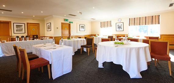 Meeting room with round and rectangular tables in white linen and red chairs