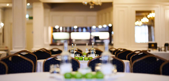 Close-up of a meeting table with water bottles and apples beside patterned chairs