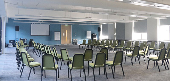 Meeting room with green chairs arranged in a semi-circle beside a blue accent wall