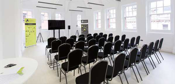 Bright white room set theatre-style with black stacking chairs