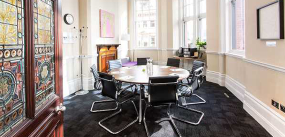 Round meeting table with black chairs beside a stained-glass door