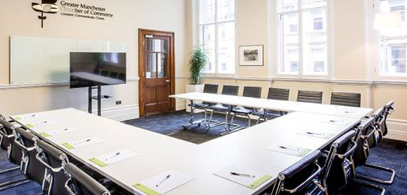 Long boardroom table with black chairs in a wood-panelled room