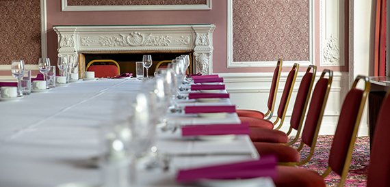 Long table dressed with pink napkins and patterned red chairs