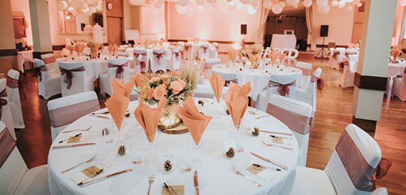Hall set with round tables, orange napkins and balloon lettering
