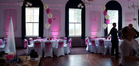 Hall set with pink chair sashes, balloons and pink uplighting