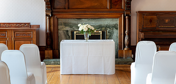 Ceremony table with flowers set before an ornate marble fireplace